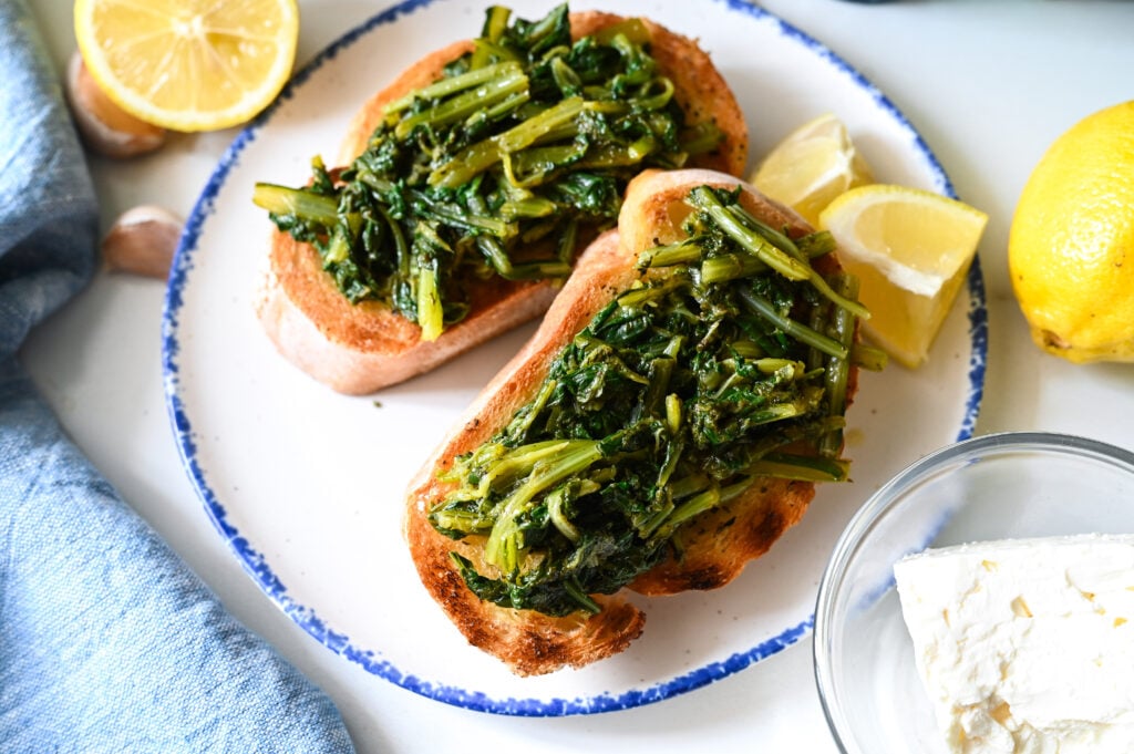 An open-face sandwich of dandelion greens and grilled bread flavoured with lemon, olive oil, garlic, oregano and feta