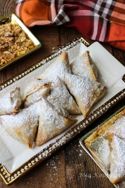 Mini apple pies with phyllo on a white platter.