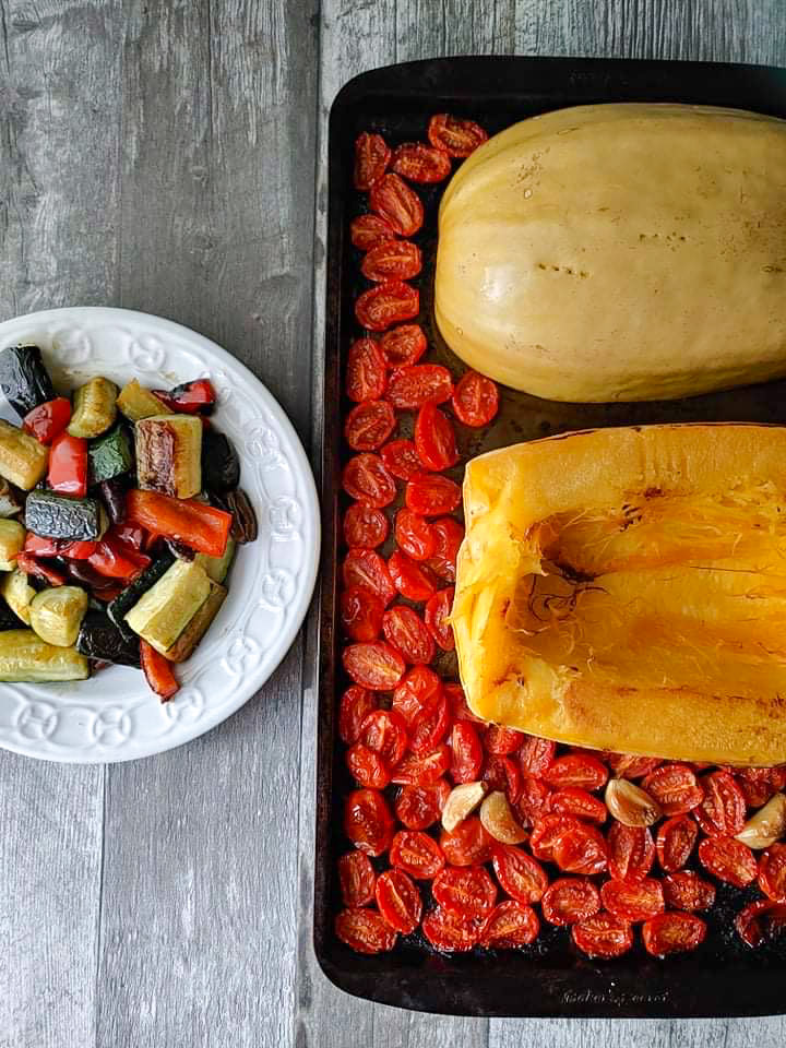 A vegan tray bake make of spaghetti squash topped with a variety of roasted vegetables.