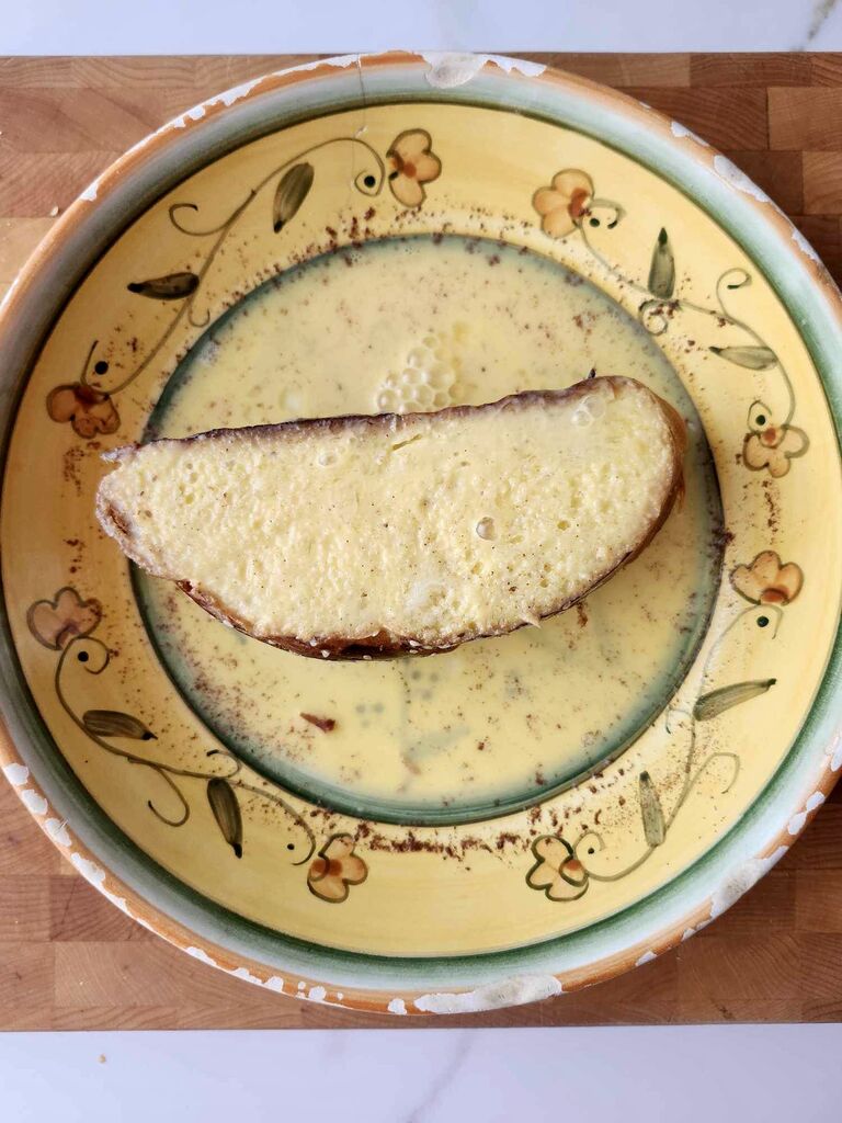 Coating the tsoureki slices with egg and milk mixture.