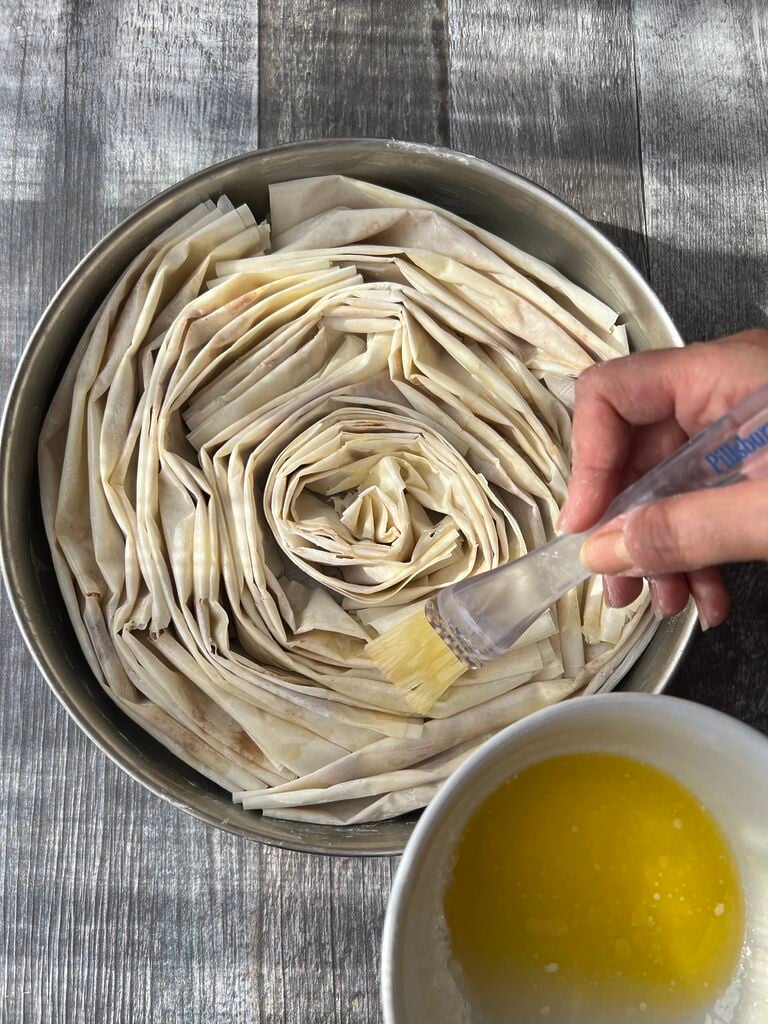 Buttering the phyllo (filo) circles.