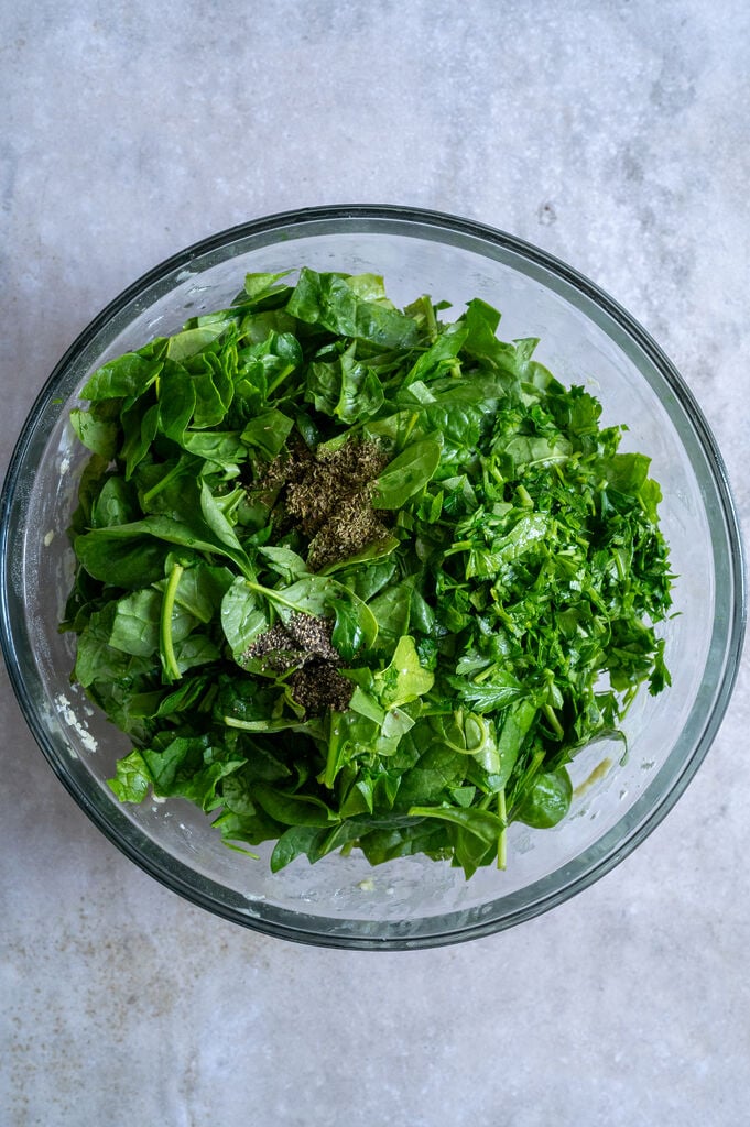 Spinach, parsley, pepper and oregano in a glass bowl.