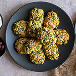 Greek Spanakotiropitakia (spinach and cheese pita) without phyllo, on a black plate surrounded by feta and olives.