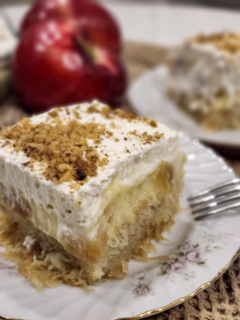 A piece of the cake on a white plate surrounded by apples.