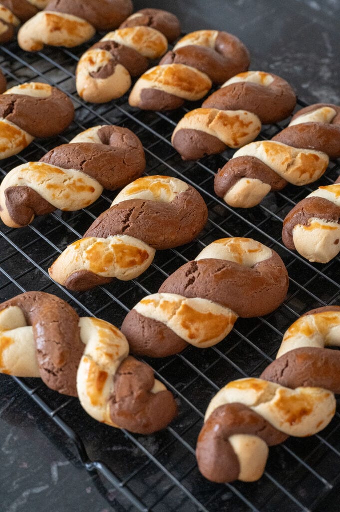 Greek butter koulourakia with a chocolate twist on a wire rack.