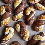 Greek butter koulourakia with a chocolate twist on a baking tray.