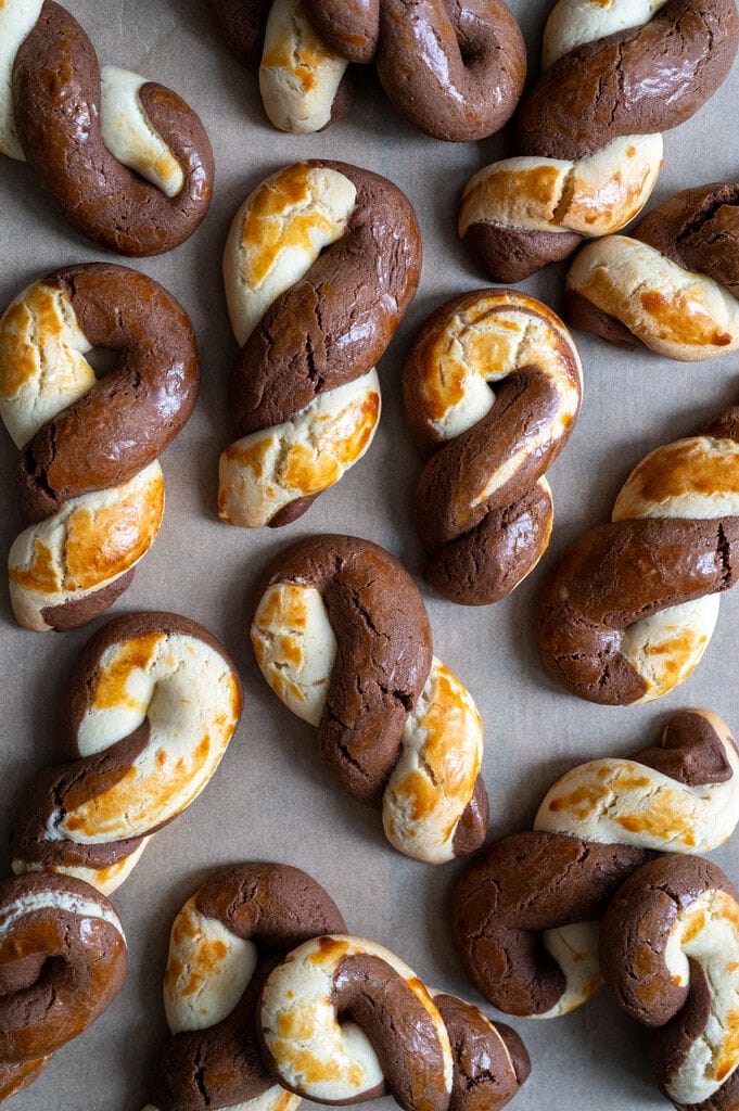 Greek butter koulourakia with a chocolate twist on a baking tray.