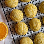 Orange ricotta cookies on parchment paper and cooling rack.