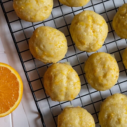 Orange ricotta cookies on parchment paper and cooling rack.