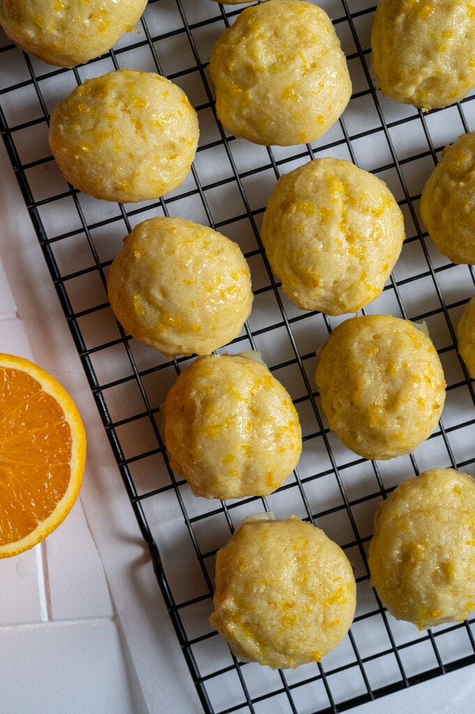 Orange ricotta cookies on parchment paper and cooling rack.