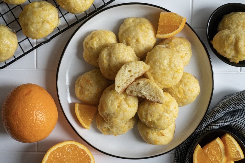 Orange ricotta cookies on a plate, and one of them is cut up.
