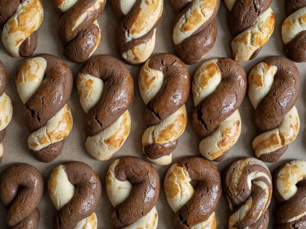 Greek butter koulourakia with a chocolate twist on a baking tray.