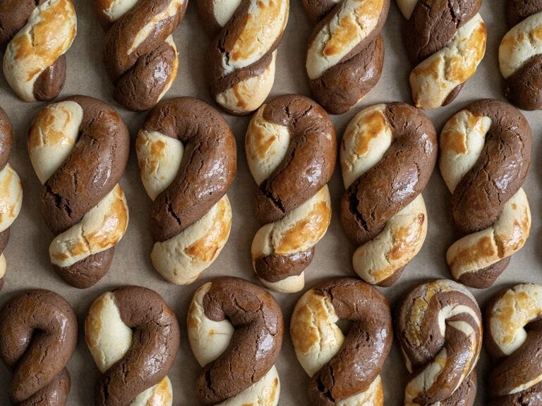 Greek butter koulourakia with a chocolate twist on a baking tray.