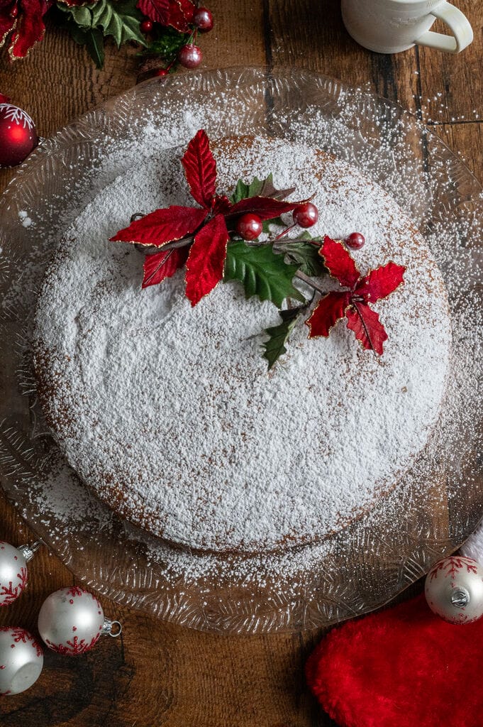Vasilopita or Greek New Year Cake (Βασιλόπιτα), on a glass platter surrounded by Christmas decorations.