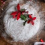 Vasilopita or Greek New Year Cake (Βασιλόπιτα), on a glass platter surrounded by Christmas decorations.