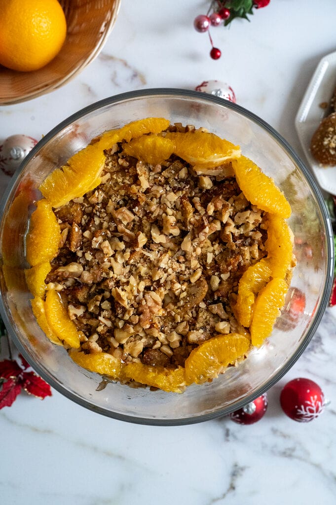 Layering the Greek melomakarona trifle in a glass trifle bowl.