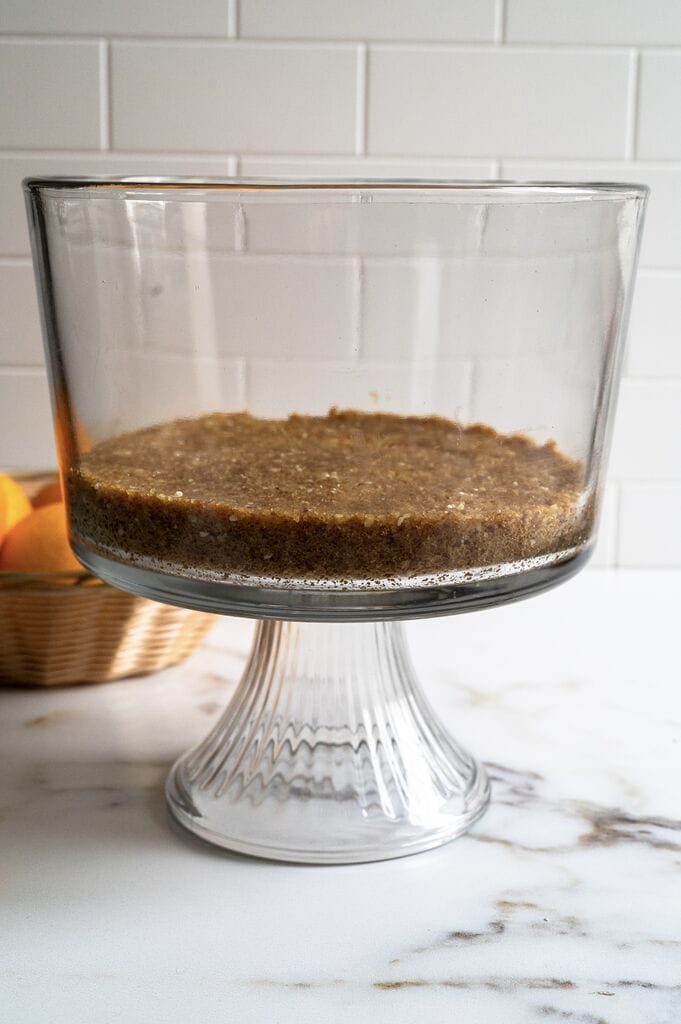 Layering the Greek melomakarona trifle in a glass trifle bowl.