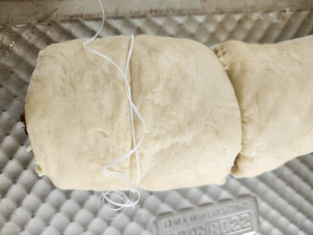 showing how to cut the individual pieces of cinnamon buns using floss.