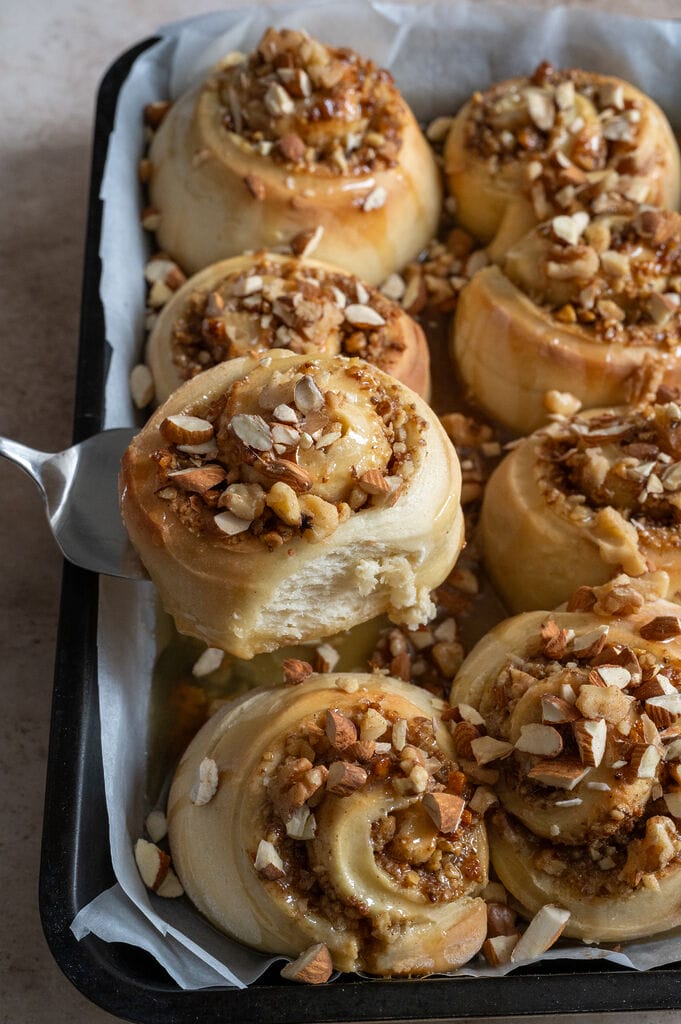 Removing a cinnamon bun from the baking tray.