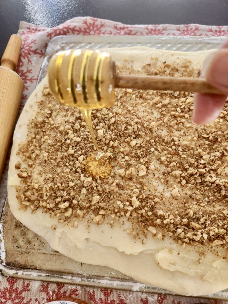 Drizzling honey over the mixture of the cinnamon buns.