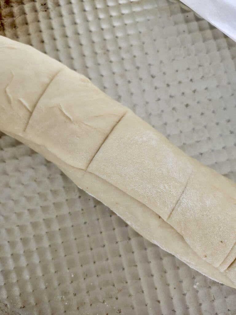 Cutting the cinnamon rolls into rolls.