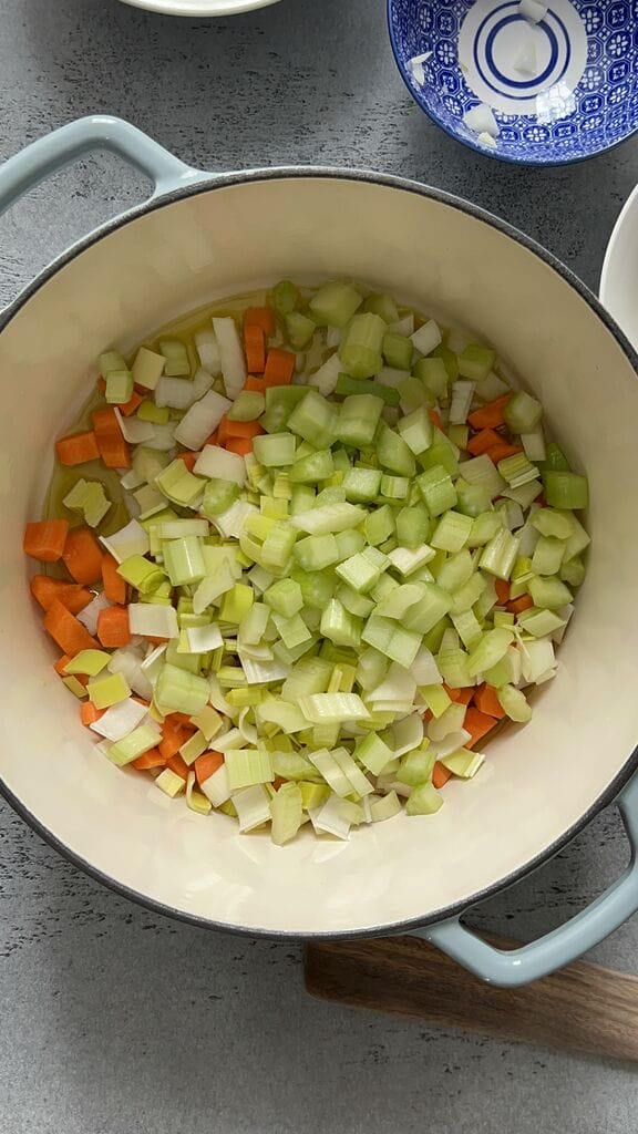 Getting ready to sauté the vegetables in a blue cast iron pot.