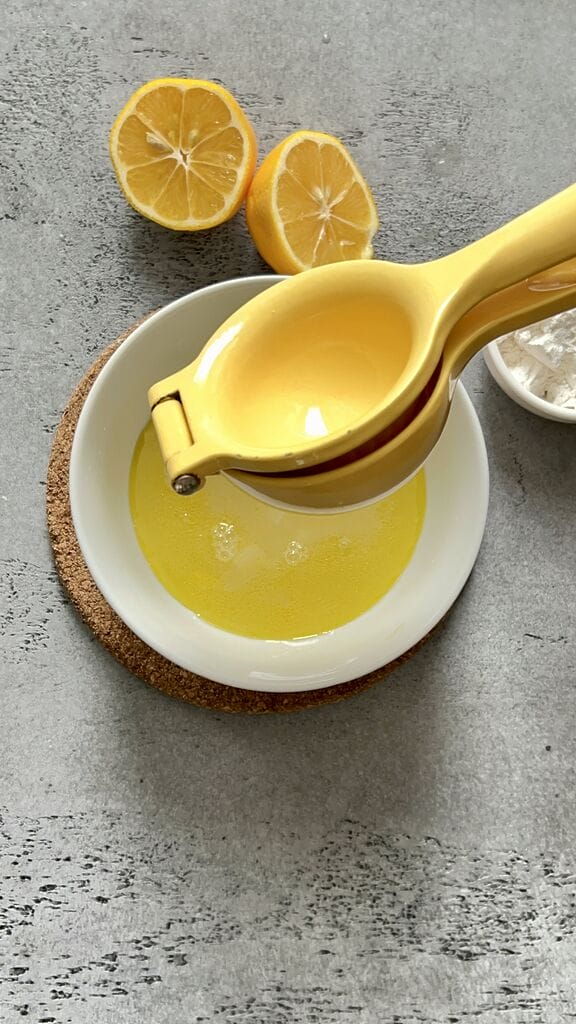 Squeezing lemon juice into a white bowl.