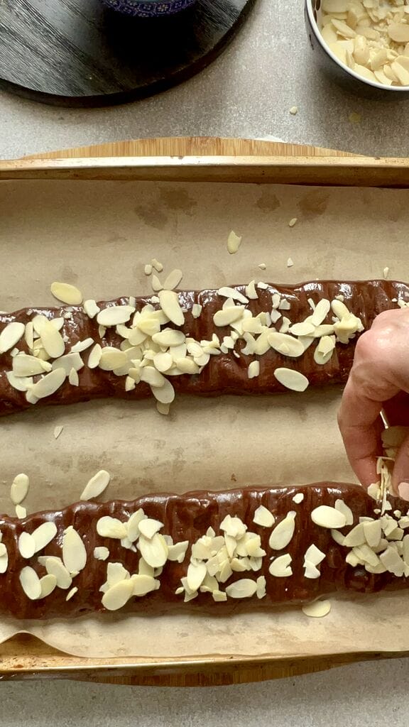Adding sliced almonds on top of the chocolate biscotti dough.