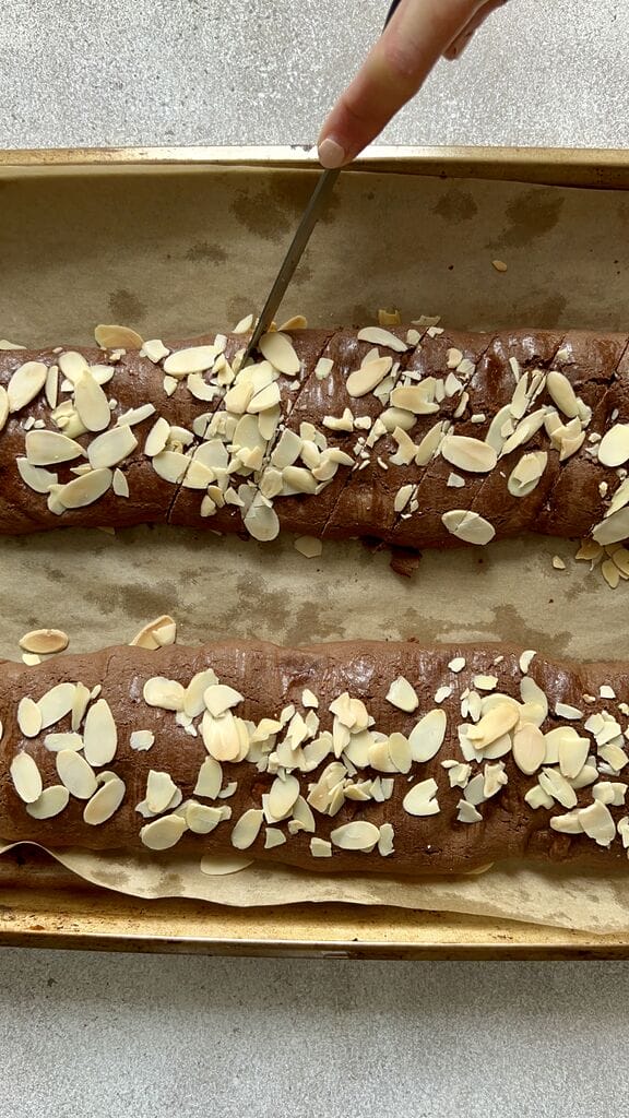 Baking the Easy Italian chocolate biscotti on a parchment lined baking sheet pan. Slicing them in pieces.