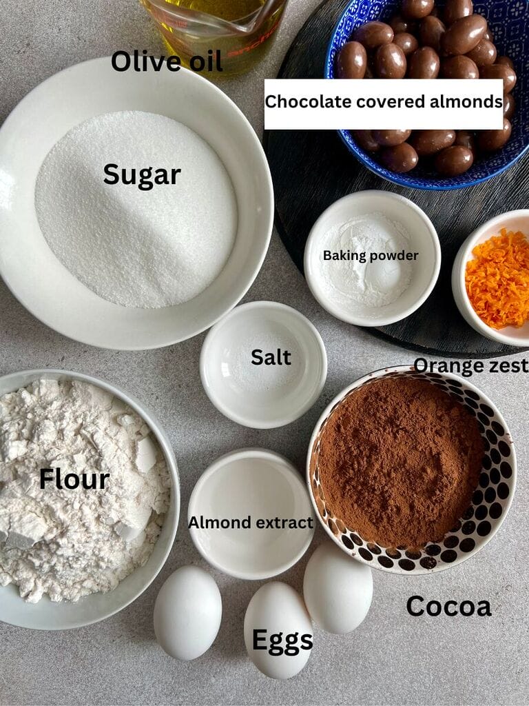 Ingredients for Easy Italian chocolate biscotti recipe which include: Sugar, olive oil, chocolate covered almonds, baking powder, salt, orange zest, almond extract, cocoa, eggs and flour.