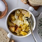 Soft boiled egg in a cup, with cubes of bread, in a white bowl.