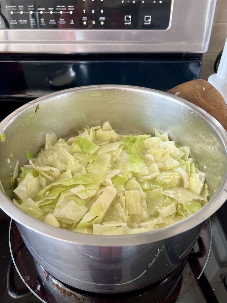 Cooking the cabbage in a stainless steel pot.