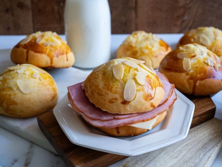 Tsoureki bread ham and cheese sandwich on a white plate.