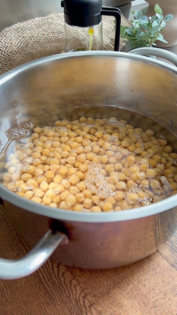 Water with chickpeas in stainless steel pot.