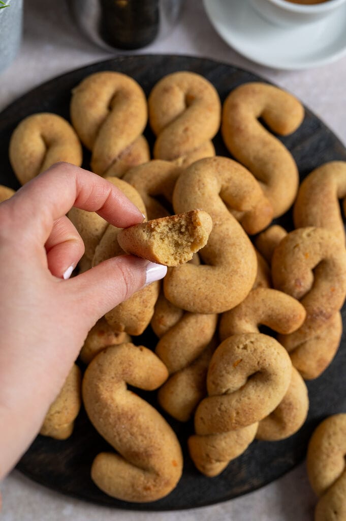 Olive oil koulourakia with orange and cinnamon on a brown wooden board.
