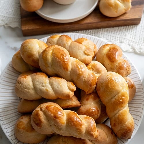 Koulourakia, a Greek cookie. Plated on a white platter with a gold trim.