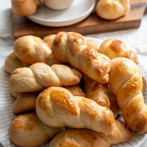 Koulourakia, a Greek cookie. Plated on a white platter with a gold trim.