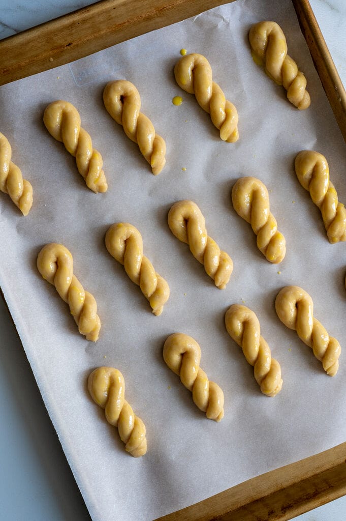 Koulourakia on a parchment lined baking pan.