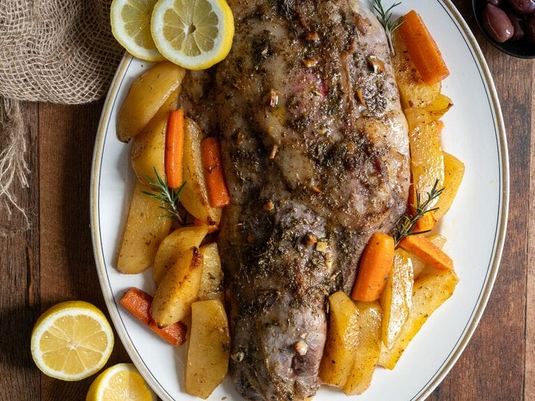 Roast lamb with potatoes on a white plate.