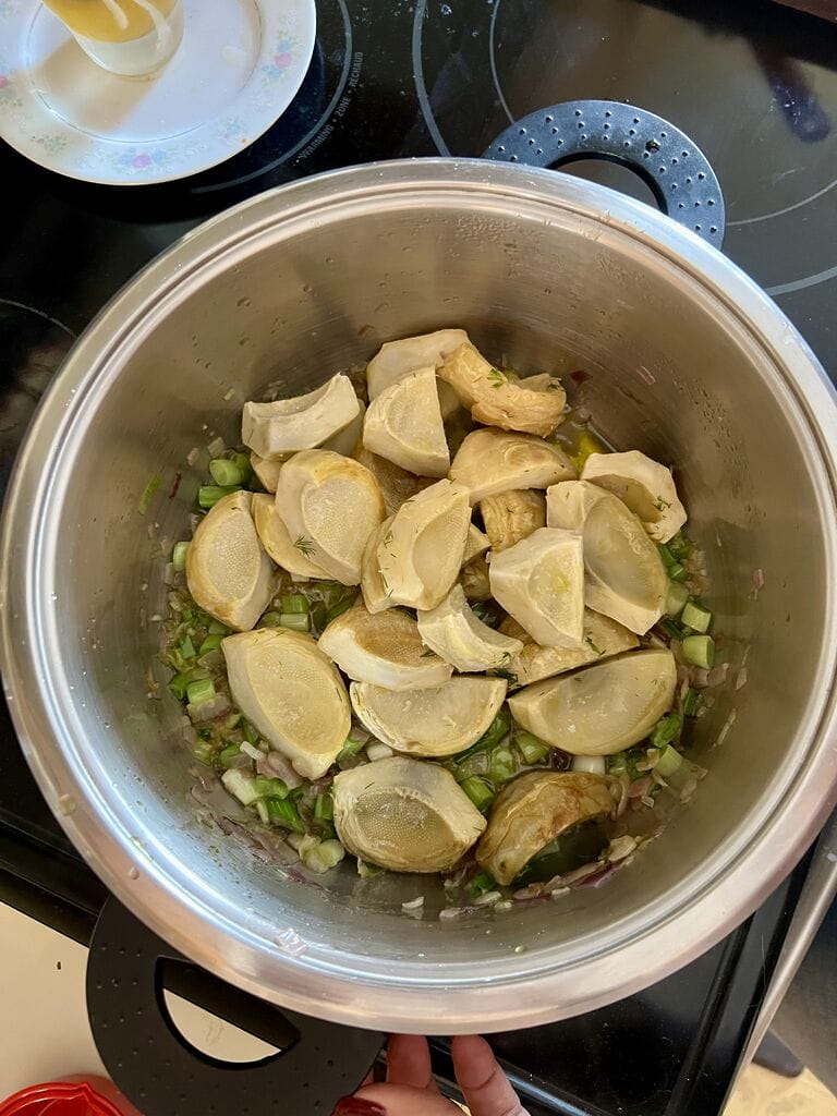 Adding the artichoke bottoms to the pot.