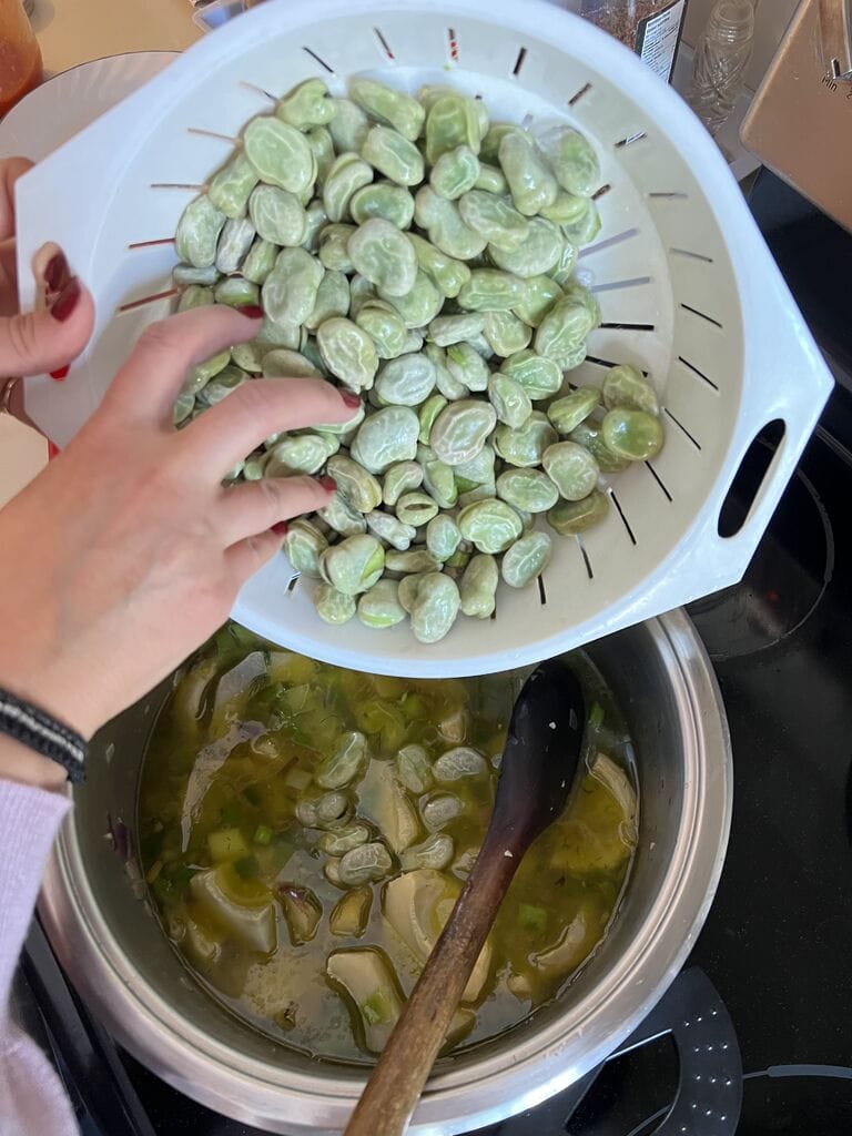 Adding the broad fava beans to the pot.