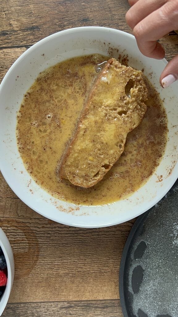 Dipping the French toast into the egg batter.