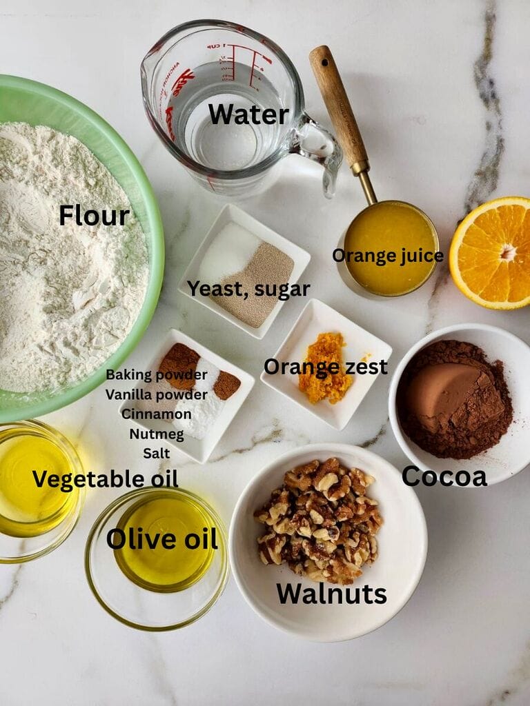 Ingredients for the Roxakia which include: Flour water, yeast, sugar, orange juice, orange zest, baking powder, vanilla powder, cinnamon, nutmeg, salt, olive oil, vegetable oil, walnuts and cocoa