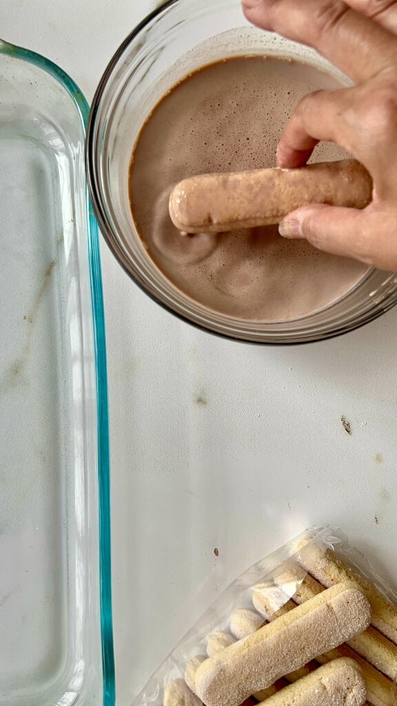 Dipping quickly the ladyfingers one at a time.