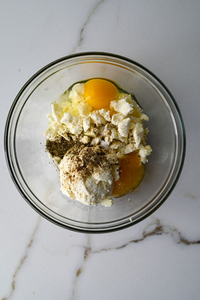Ingredients for Greek cheese top bread which includes eggs, feta, ricotta and herbs
