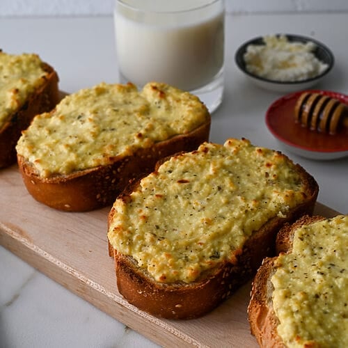 Greek cheese topped bread on a wooden platter.
