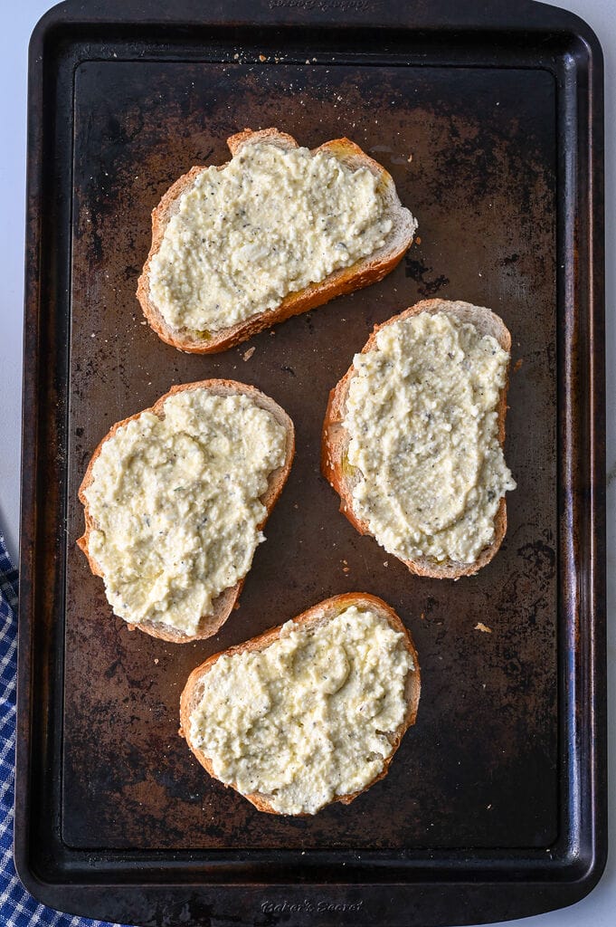 Greek cheese topped bread on a baking sheet.