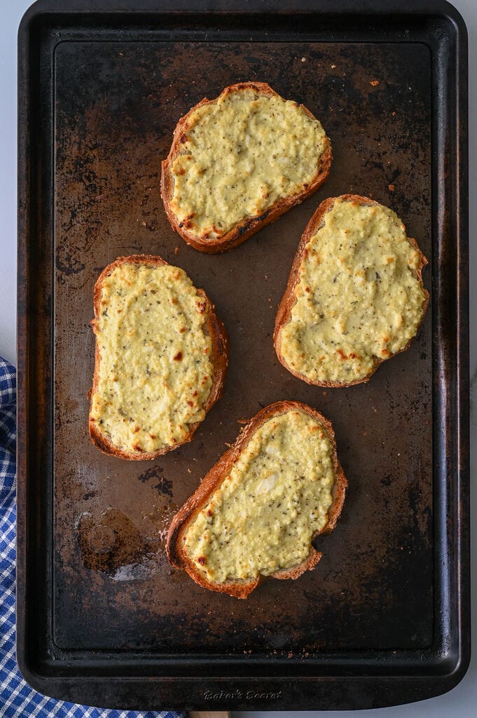 Greek cheese topped bread on a baking sheet.
