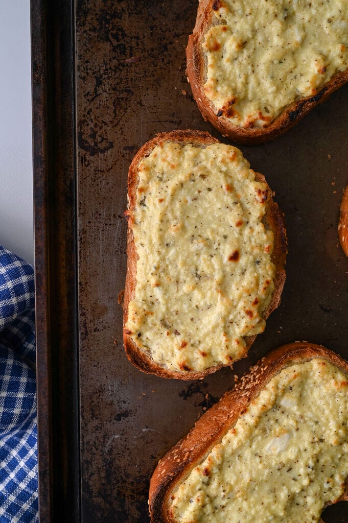 Greek cheese topped bread on a baking sheet.