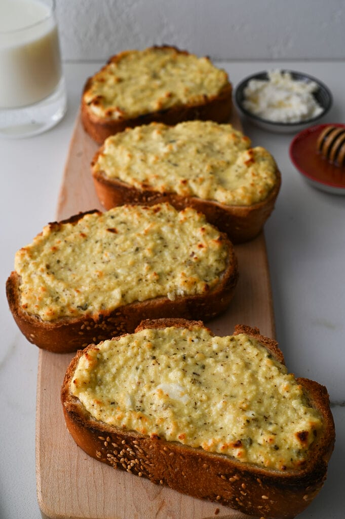 Greek cheese topped bread on a wooden platter.
